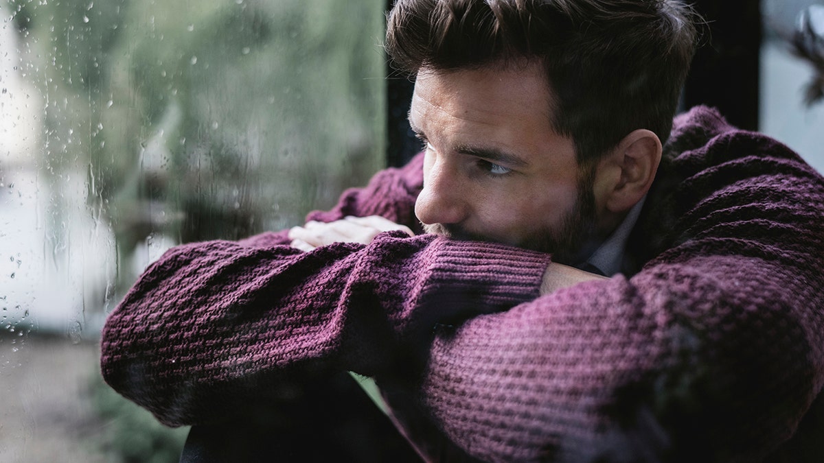 man depressed looks out the window