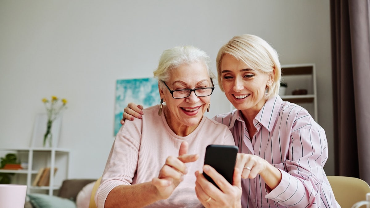 senior looking at smartphone with family member