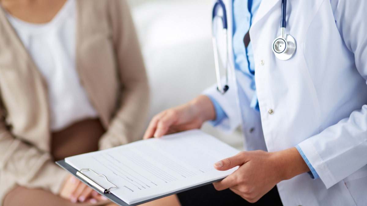 Female doctor holding application form while consulting patient