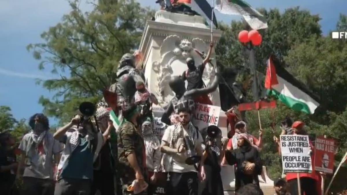 Protesters stand on defaced statue