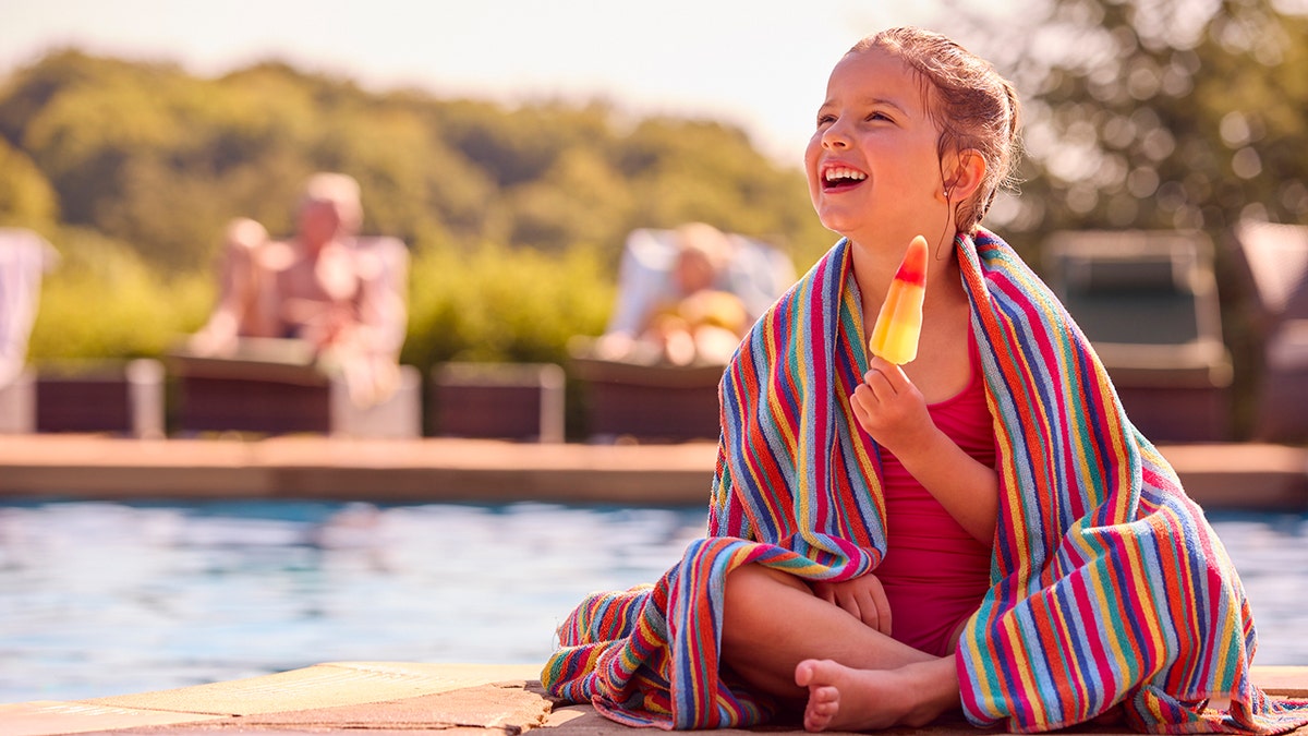 little-girl-eating-ice-pop-by-pool