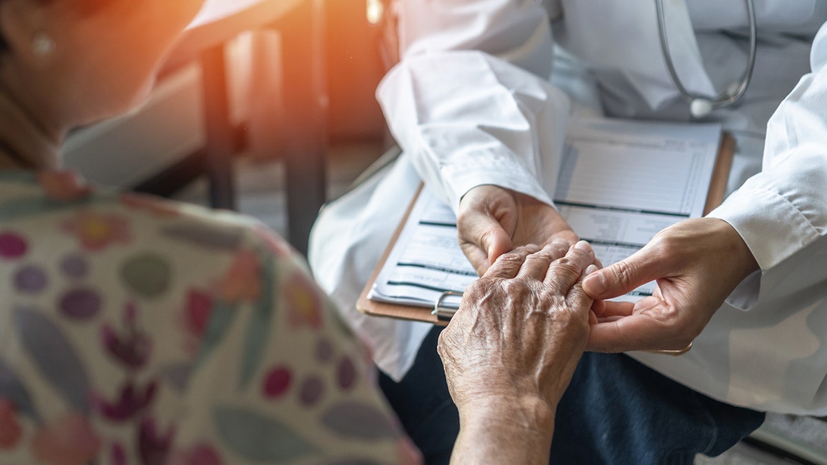 Parkinson's disease patient holding doc tor's hand