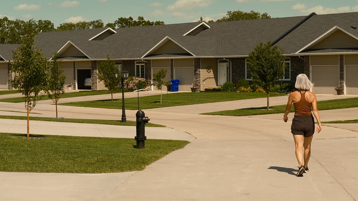Senior woman in shorts and tank top going for a walk around empty condo complex.