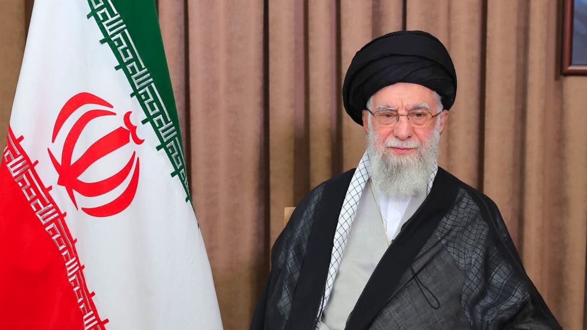 Iranian Supreme Leader Ali  Khamenei seated beside the Iranian flag during an address.