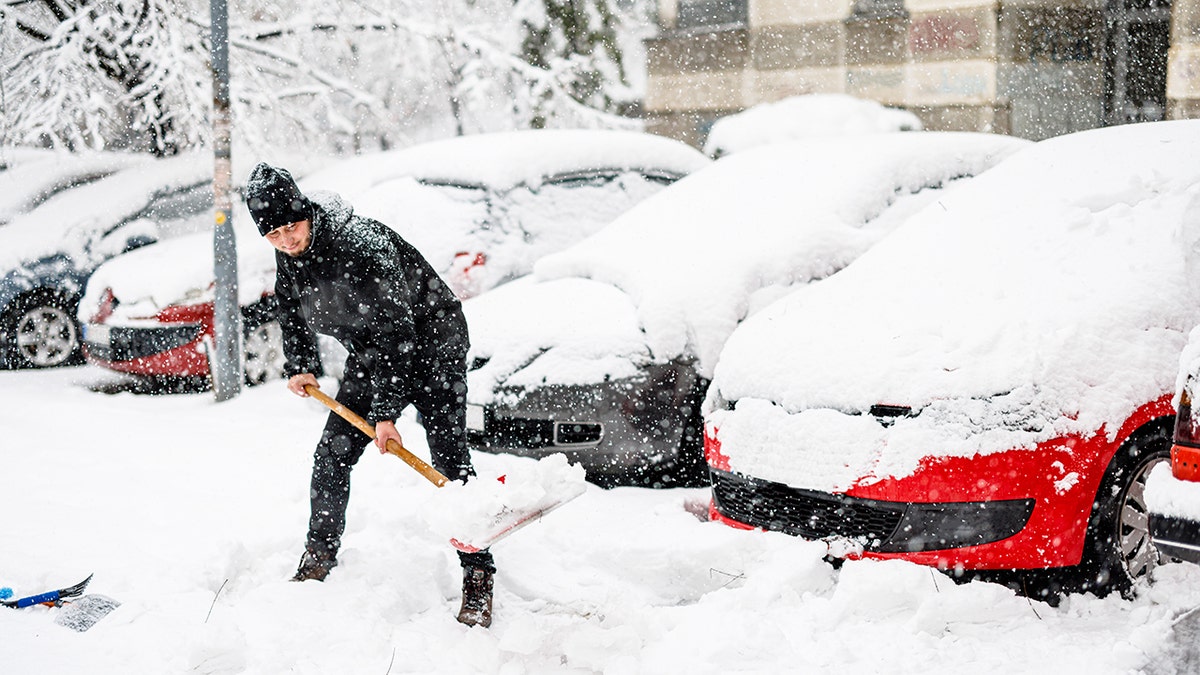man shovels heavy snow off sidewalk