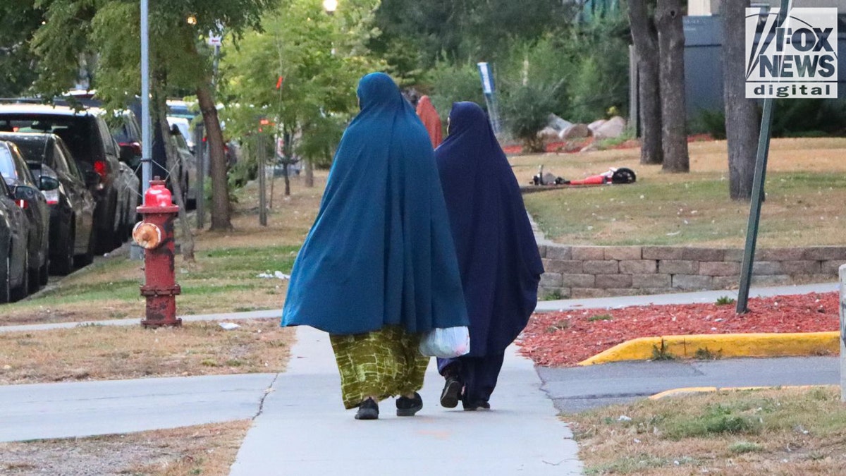 Two women wearing traditional Muslim clothing walking on a sidewalk in Minneapolis.