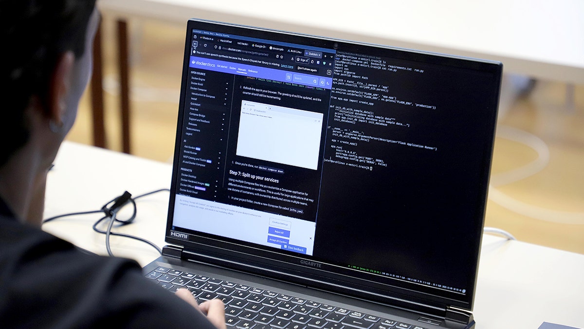 A person uses a computer with coding on the screen.