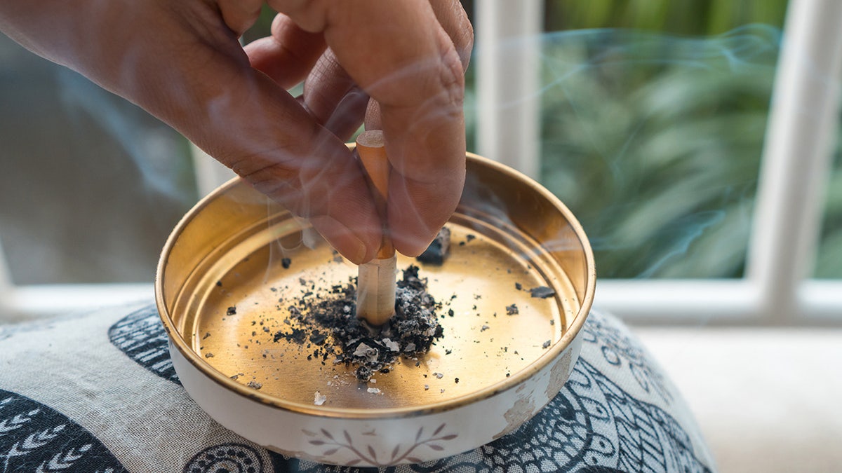 Close-up of a woman putting out a cigarette in a golden ashtray