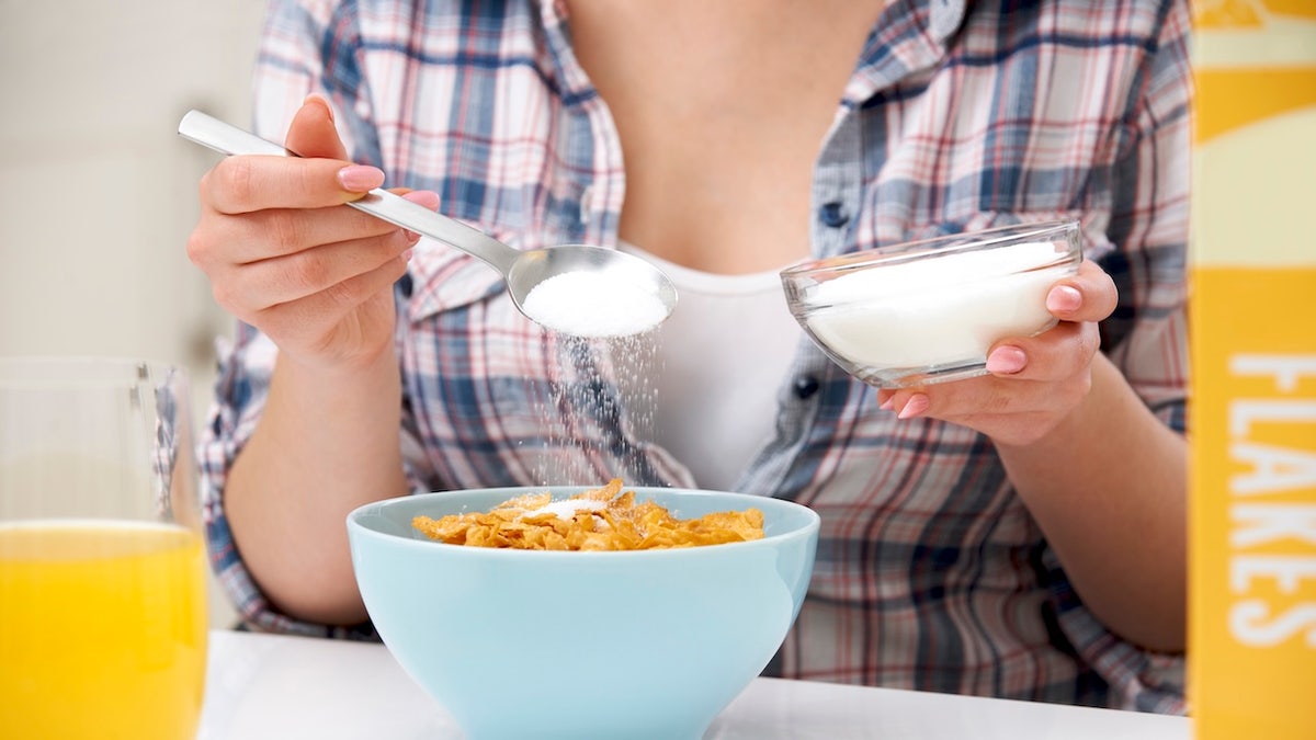 Woman adding sugar to breakfast cereal