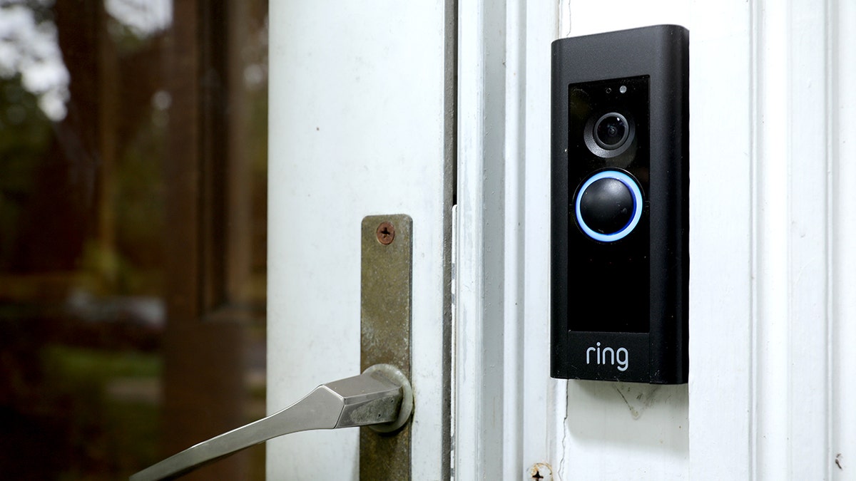 A Ring doorbell camera is seen next to a glass door.
