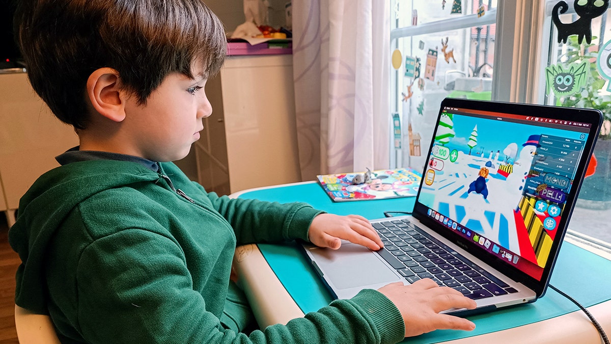 A child plays Roblox on a laptop.