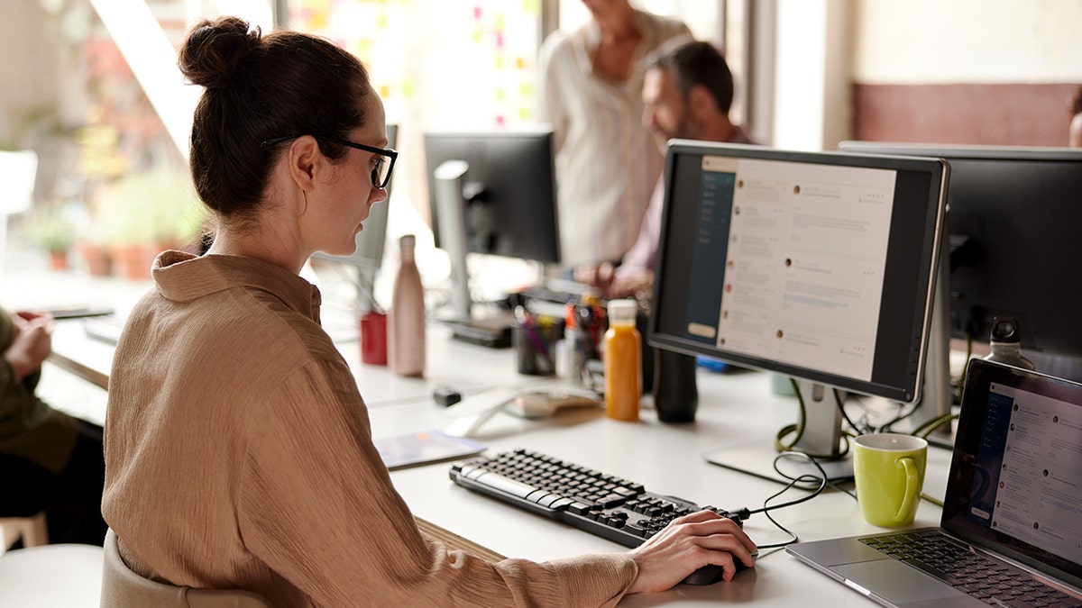 A woman uses a computer in an office setting.